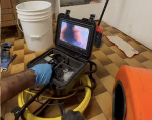 Professional plumber performing drain camera inspection and tree root removal in Toronto residential home