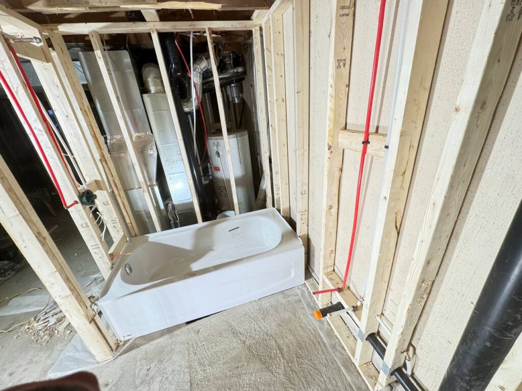 Professional plumbers installing PVC hot cold water piping and drainage in residential basement renovation Toronto