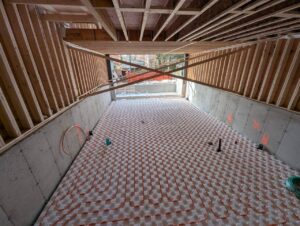 Professional plumbers installing radiant floor heating and furnace room piping in new custom residential home Toronto